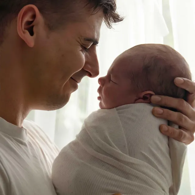 Papá mirando con ternura a su bebé recién nacido en brazos